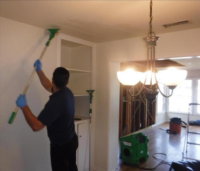 A technician wiping down walls with sponge to get rid of ash.