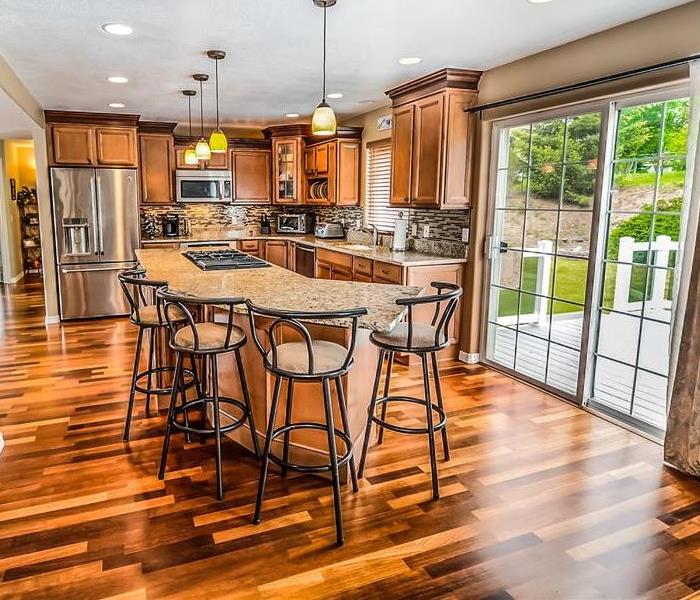A kitchen with shiny multi-colored brown hardwood floor.